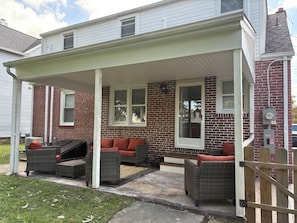 A covered patio with wicker furniture and a brick exterior. - Deluxe 4 BR 2 BA Neighborhood Gem (Wilmington)