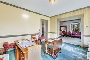 Ein Zimmer mit Schreibtisch, Stühlen, einem Rollstuhl und einem Essbereich mit Stühlen und Tisch.