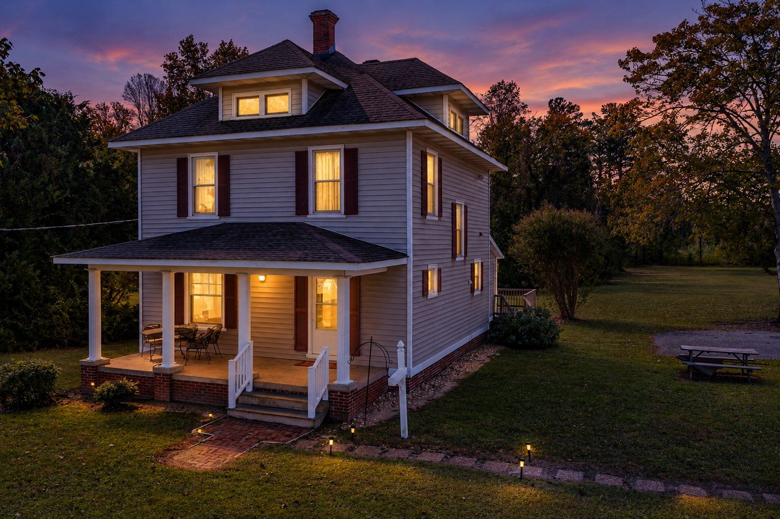 A two-story house with a porch and a well-lit front entrance.