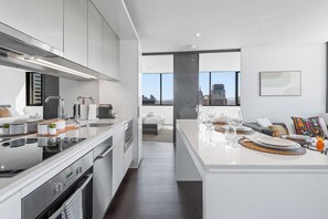 Een moderne keuken met roestvrijstalen apparatuur, een eethoek met uitzicht op de stad, en een minimalistische woonruimte.