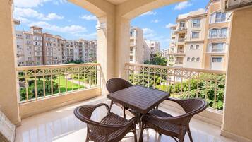 A balcony with a table and chairs, overlooking a residential area with apartment buildings.