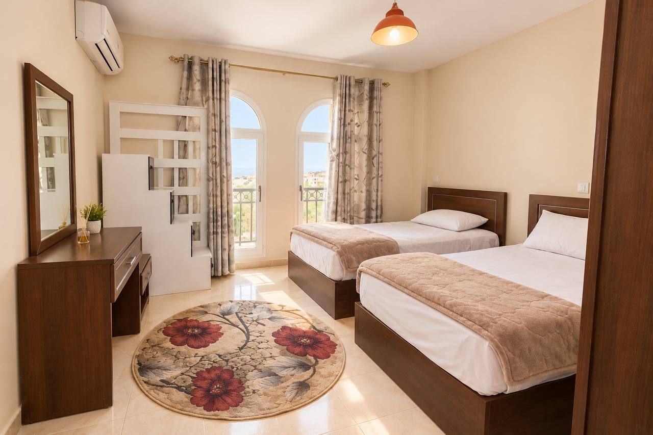 Une chambre d’hôtel avec deux lits, un bureau, un miroir et une vue sur l’extérieur.