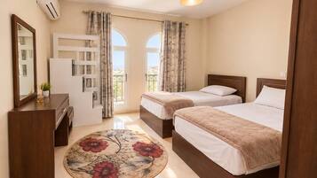 Une chambre d’hôtel avec deux lits, un bureau, un miroir et une vue sur l’extérieur.