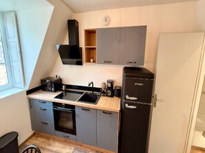 A compact kitchen with a built-in oven, a sink, and a black refrigerator. - Mont-dore Apartment, Mountain View (Mont-Dore)