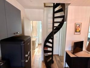 A modern interior with a spiral staircase, a black filing cabinet, and a flat-screen TV. - Mont-dore Apartment, Mountain View (Mont-Dore)