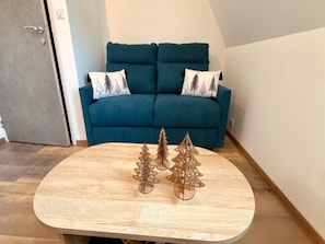A living room with a teal sofa, two decorative wooden Christmas trees, and a wooden coffee table. - Mont-dore Apartment, Mountain View (Mont-Dore)