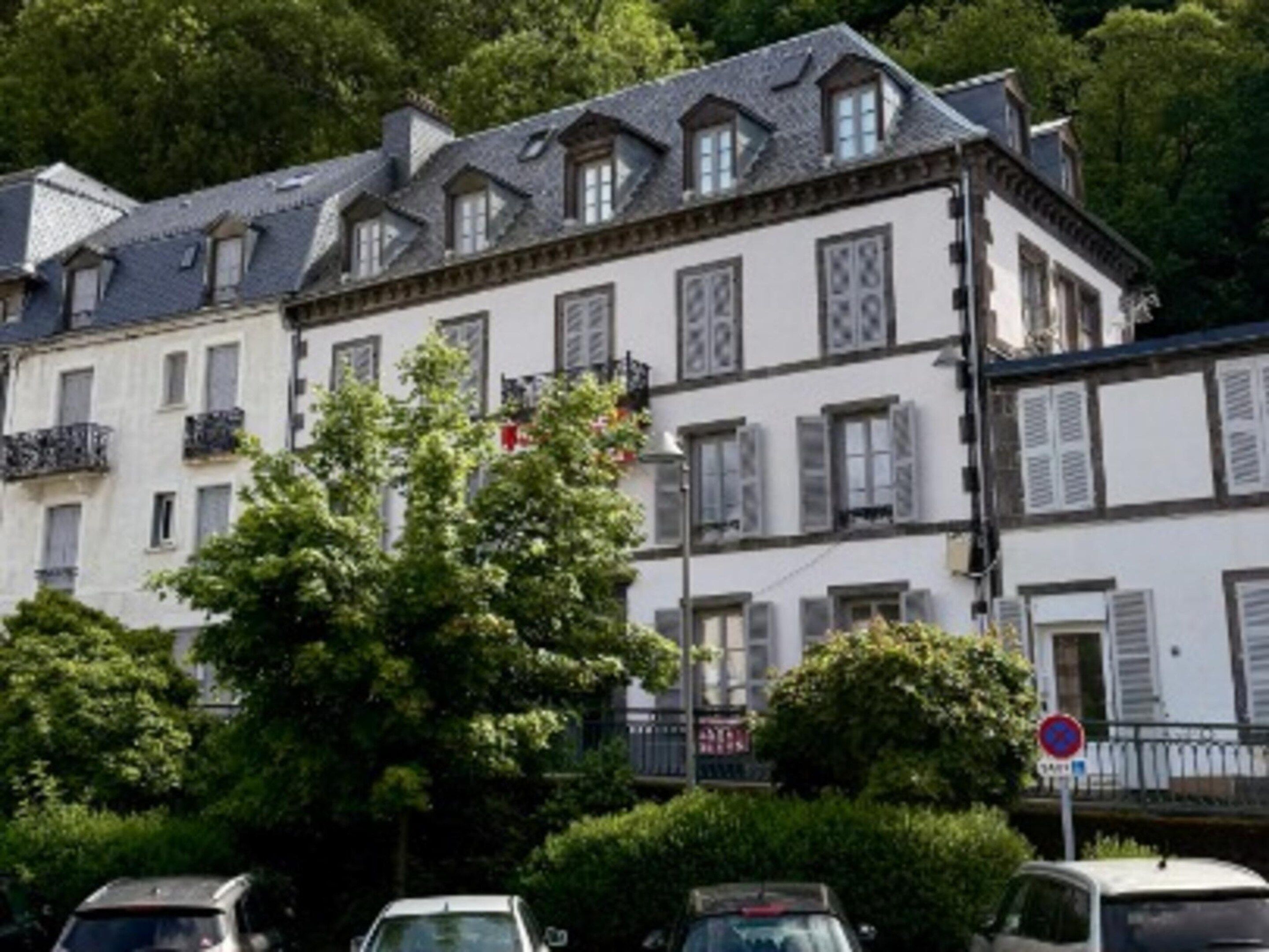 A multi-story building with a classic architectural style, featuring symmetrical windows and a balcony.