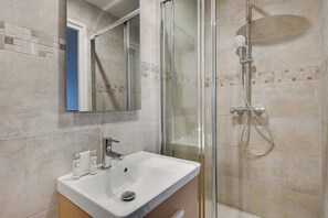 A bathroom with a glass-enclosed shower, a white sink, and a mirror above the sink. - Charming Studio - 2P - Next to Paris (Le Kremlin-Bicetre)