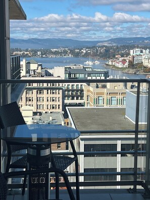 Un balcone con vista su un paesaggio urbano, che include edifici e un corpo d'acqua.