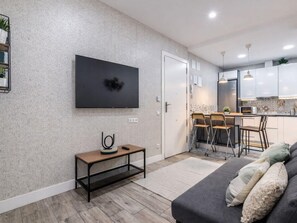 A modern living room with a flat-screen TV, a small table, and a sofa with cushions. - Apartment Near Retiro Park (Madrid)