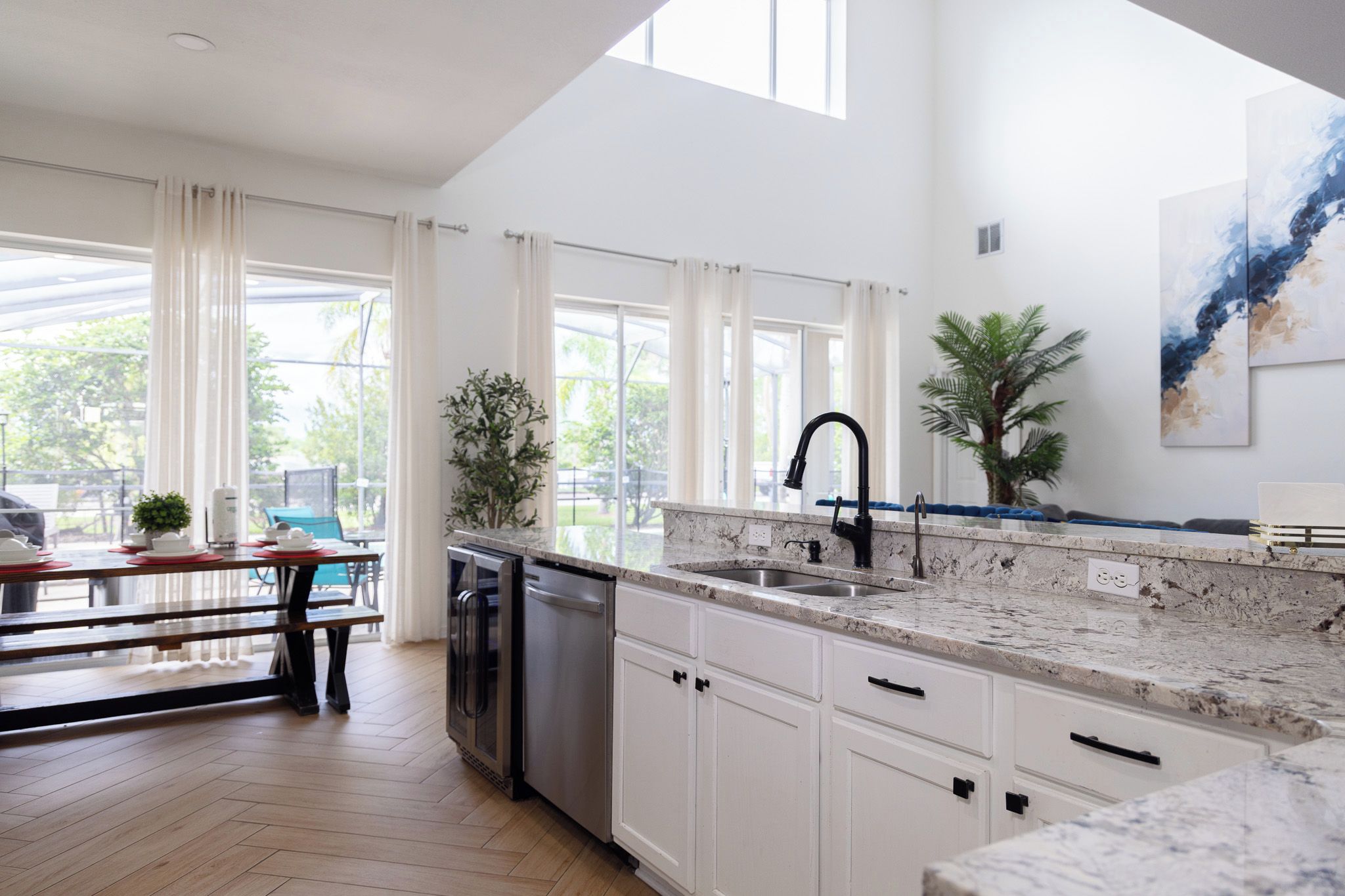 A modern kitchen with white cabinetry, a granite countertop, and a black faucet.