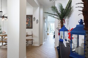 A hallway with a wooden floor, a dining area with a table and chairs, and a blue decorative lantern. - 7BR Villa Near Disney / FREE Pool Heat, Hot Tub, Game Room / Sleeps 14 (Clermont)