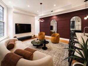 A modern living room with a sofa, armchairs, a coffee table, and a TV. - Timeless Elegance on RQ | By Rafa Properties (Philadelphia)