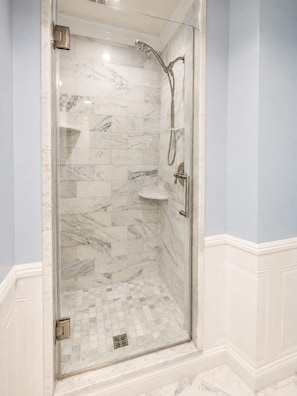 A glass-enclosed shower with marble tiles and a white pedestal sink. - Timeless Elegance on RQ | By Rafa Properties (Philadelphia)