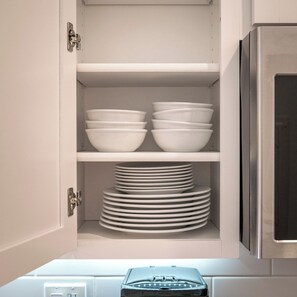 A kitchen cabinet with white shelves holding bowls and stacked plates. - Stylish 1BD near UPenn & Drexel | Queen Bed (Philadelphia)