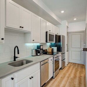 A modern kitchen with white cabinets, stainless steel appliances, and a wooden floor. - Stylish 1BD near UPenn & Drexel | Queen Bed (Philadelphia)