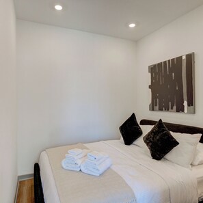 Una habitación de hotel con una cama bien hecha, un cuadro abstracto grande en la pared y suelo de madera.