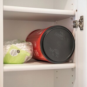 Un armario de almacenamiento con un recipiente rojo y una bolsa de plástico verde.