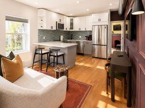 A modern kitchen with white cabinets, a central island, stainless steel appliances, and a dining area with a table and chairs. - Chic 1BD in RittenHouse Sq | Balcony (Philadelphia)