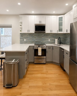 A modern kitchen with white cabinets, a stainless steel refrigerator, a built-in oven, and a microwave. - Chic 1BD in RittenHouse Sq | Balcony (Philadelphia)