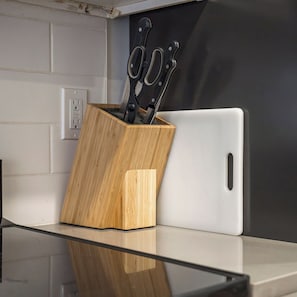 A kitchen counter with a wooden knife block and a white tablet. - Sleek Studio near UPenn & Drexel | King Bed (Philadelphia)