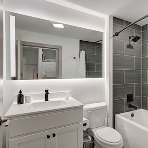 A modern bathroom with a white vanity, a toilet, and a bathtub. - Sleek Studio near UPenn & Drexel | King Bed (Philadelphia)