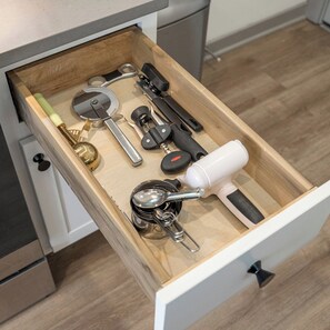 A drawer with various kitchen utensils including a rolling pin, a can opener, and a measuring cup. - Comfortable 1BD near UPenn & Drexel | Queen Bed (Philadelphia)