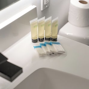 A bathroom counter with four tubes of ECO shampoo and four packets of Juviale face and body wash. - Comfortable 1BD near UPenn & Drexel | Queen Bed (Philadelphia)