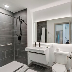 Een moderne badkamer met douche, toilet en wastafel.
