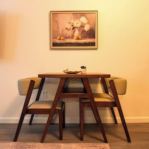Ein Essbereich mit einem Holztisch, zwei Stühlen, einer Blumenvase und einem Gemälde an der Wand.