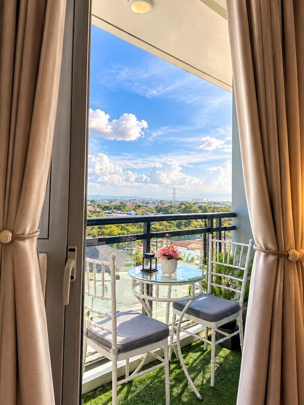 Un balcone con un tavolino in vetro, due sedie e un vaso di fiori.