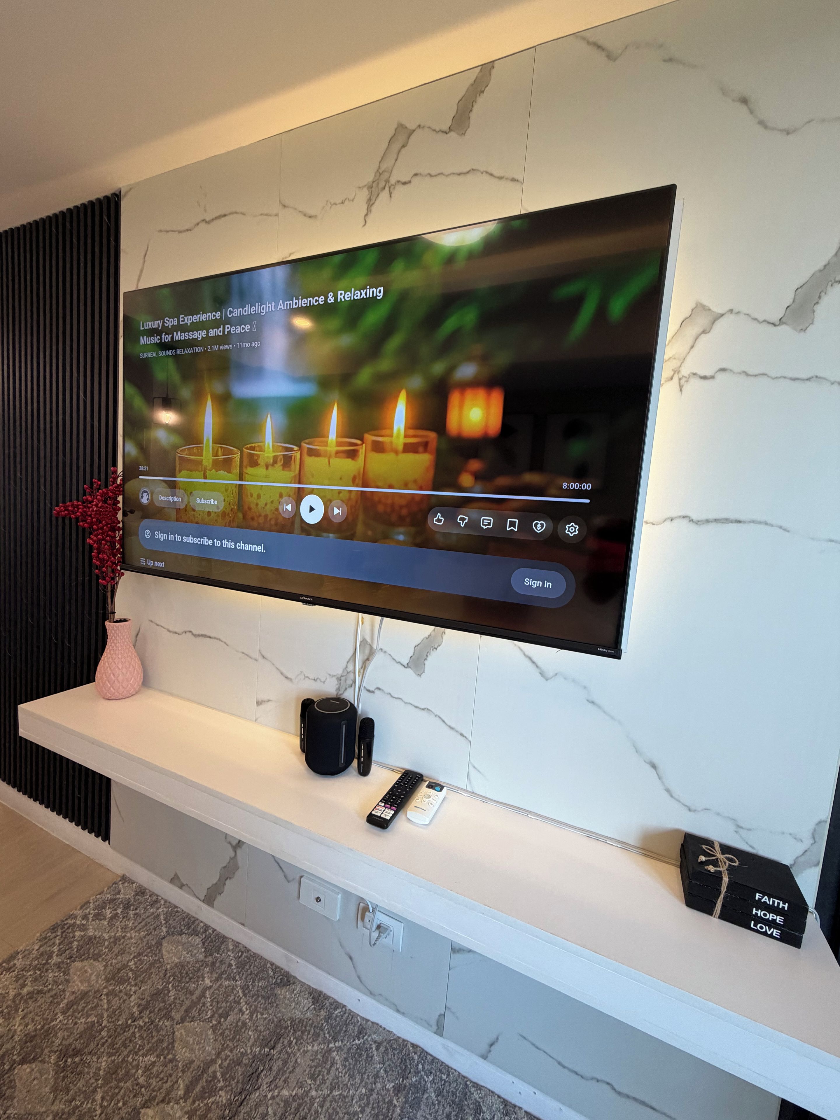 Una TV a schermo piatto montata su una parete in marmo, con la riproduzione di un video musicale a tema spa.