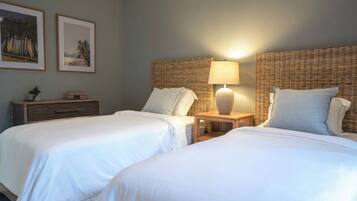 A hotel room with two beds, a nightstand with a lamp, and two framed pictures on the wall.