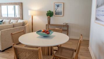 A cozy living area with a round table, wicker chairs, a sofa, and a lamp.