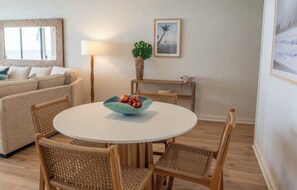 A cozy living area with a round table, wicker chairs, a sofa, and a lamp. - Poipu Makai Luxury Oceanfront Condo with AC & Sunset Views (Koloa)