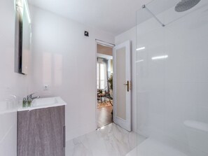A modern bathroom with a white vanity, a shower area, and a door leading to a living space. - Penthouse With Terrace, Plaza Espana (Madrid)