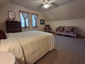 A bedroom with a large bed, a dresser, a chair, a sofa, and a ceiling fan. - Spacious Lakehouse on Lac Courte Oreilles (Stone Lake)