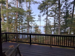 A wooden deck with a railing overlooking a forest and a body of water. - Spacious Lakehouse on Lac Courte Oreilles (Stone Lake)