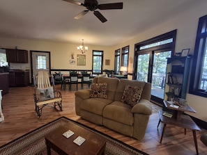 A living room with a sofa, coffee table, and a dining area with chairs and a table. - Spacious Lakehouse on Lac Courte Oreilles (Stone Lake)