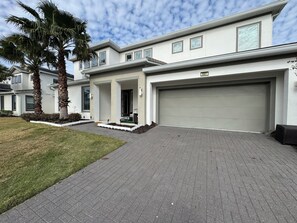 Ein modernes, zweistöckiges Haus mit Garage, überdachter Veranda und gepflegtem Rasen.