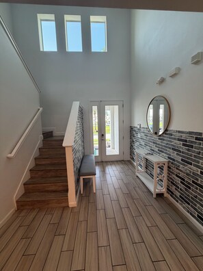 Ein Flur mit einer Holztreppe, einer Sitzbank und einer Tür, die nach draußen führt.