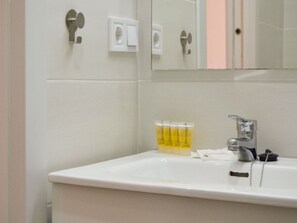 Une salle de bain avec un lavabo blanc, un miroir et des toilettes.