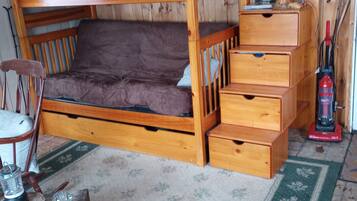 A bunk bed with a wooden headboard, a bedside table, and a small drawer unit.