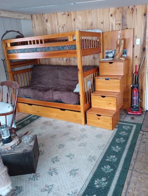 A bunk bed with a wooden headboard, a bedside table, and a small drawer unit. - Beautiful cabin in soothing Livonia perfect for a relaxing getaway. Off grid . (Livonia)