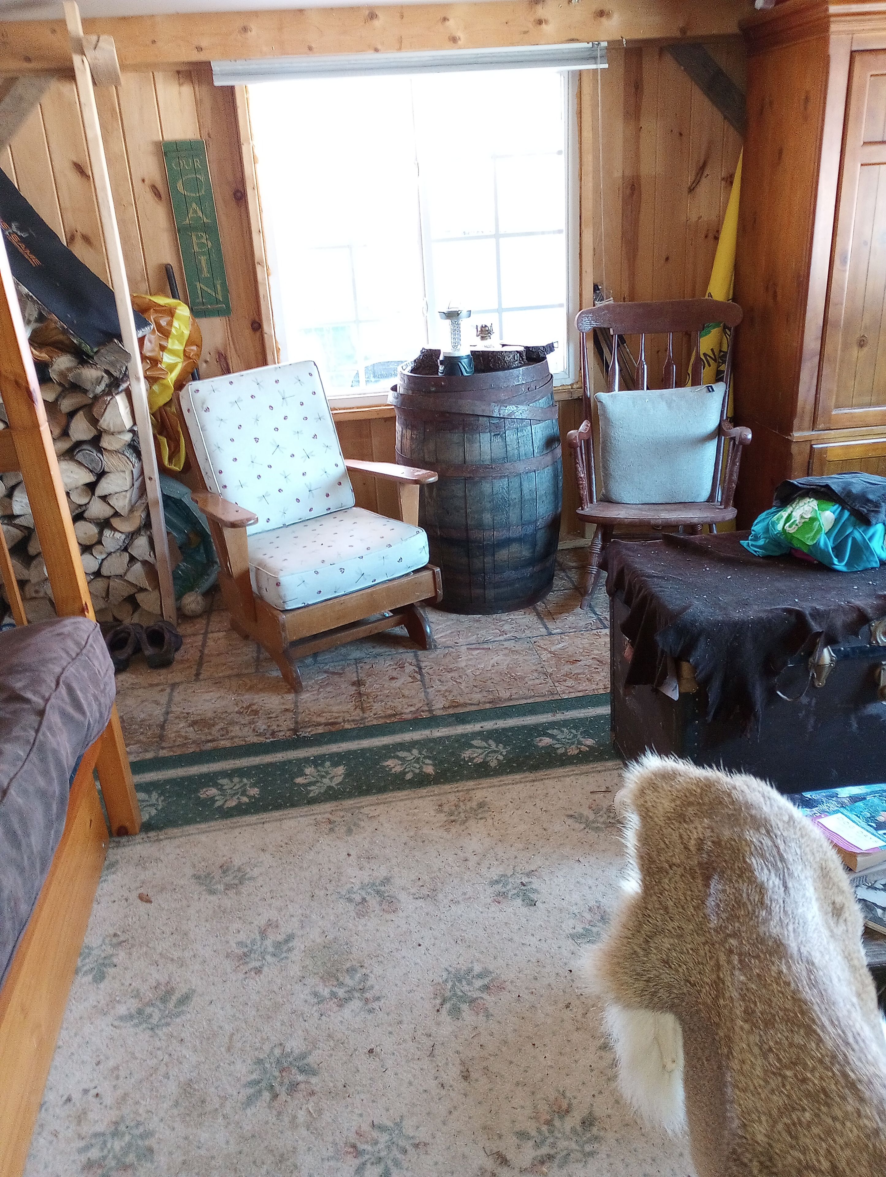 L’intérieur d’un chalet rustique, avec une chaise en bois, un tonneau et un chien.