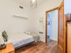 A bedroom with a bed, a bedside table, a mirror, and a wardrobe. - Spacious Apartment Near Retiro Park (Madrid)