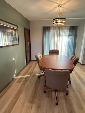 A conference room with a wooden table and cushioned chairs, a chandelier, a framed picture on the wall, and a door. - The Coteau Chateau 3-bedroom country home near Conde awaits you (Conde)