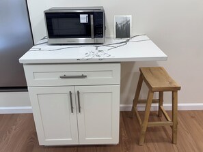 A kitchenette with a microwave, a small cabinet, and a wooden stool. - Modern Luxury 1BR Walk to Pitt, CMU & UPMC (Pittsburgh)