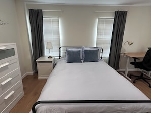 A bedroom with a bed, a desk, a chair, a dresser, and a window with curtains. - Modern Luxury 1BR Walk to Pitt, CMU & UPMC (Pittsburgh)