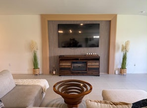 A living room with a large flat-screen TV, two sofas, a coffee table, and decorative plants. - Golden Pine Haven, Luxury 5-Bedroom Vacation Home. (Homestead)